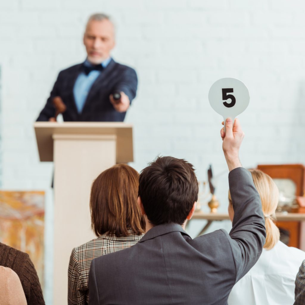 A man holds up an auction sign indicating he places a bid during a live auction.