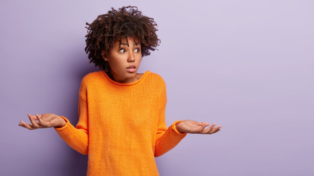 A woman shrugs her shoulders to illustrate the frustration of being in a dilemma.