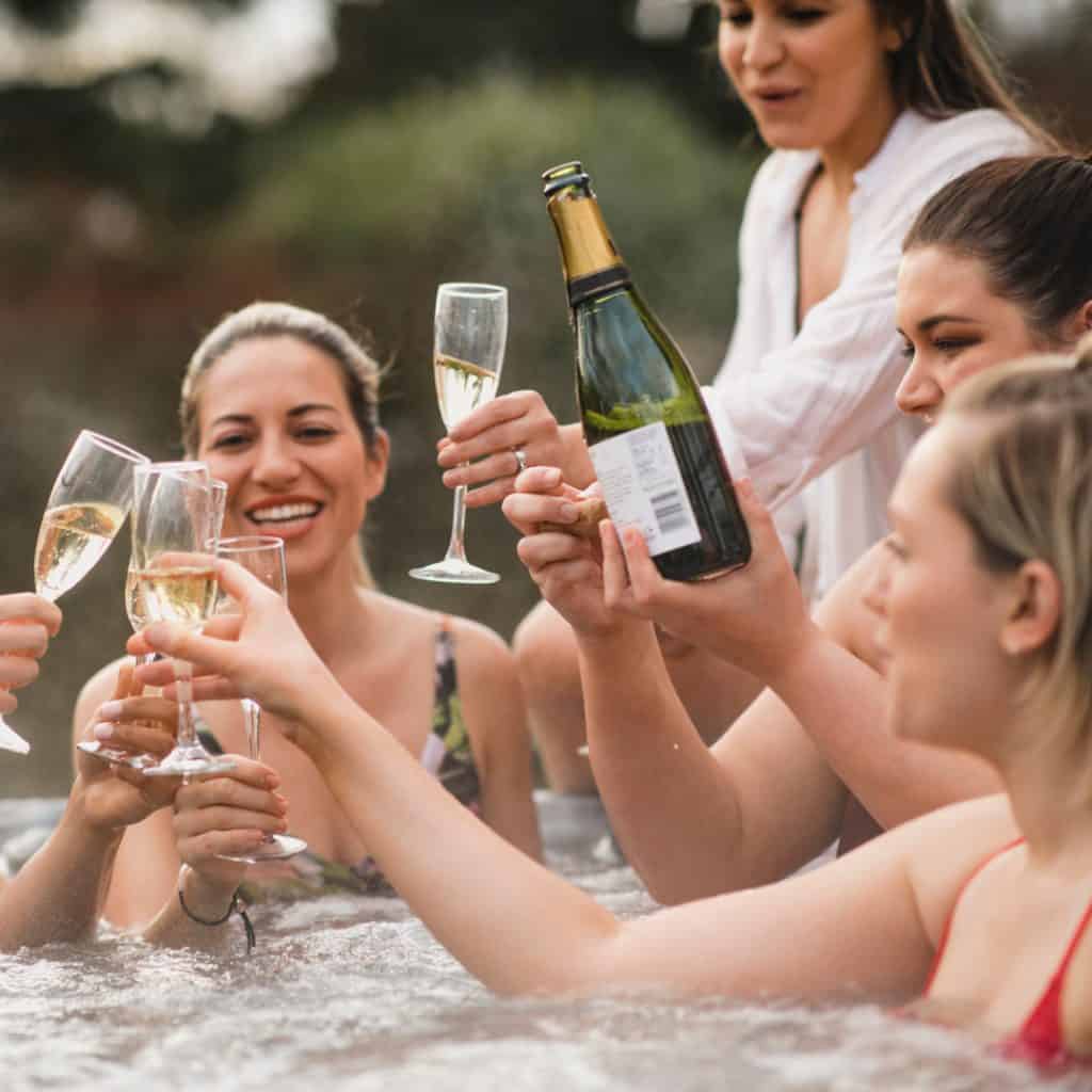 A group of close friends relax in a hot tub and enjoy a drink together.
