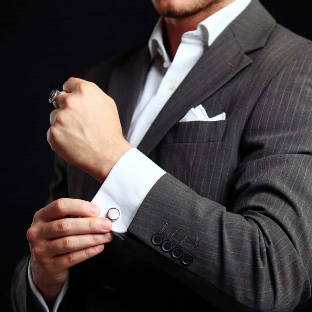 A stylish man adjusts his cufflinks.