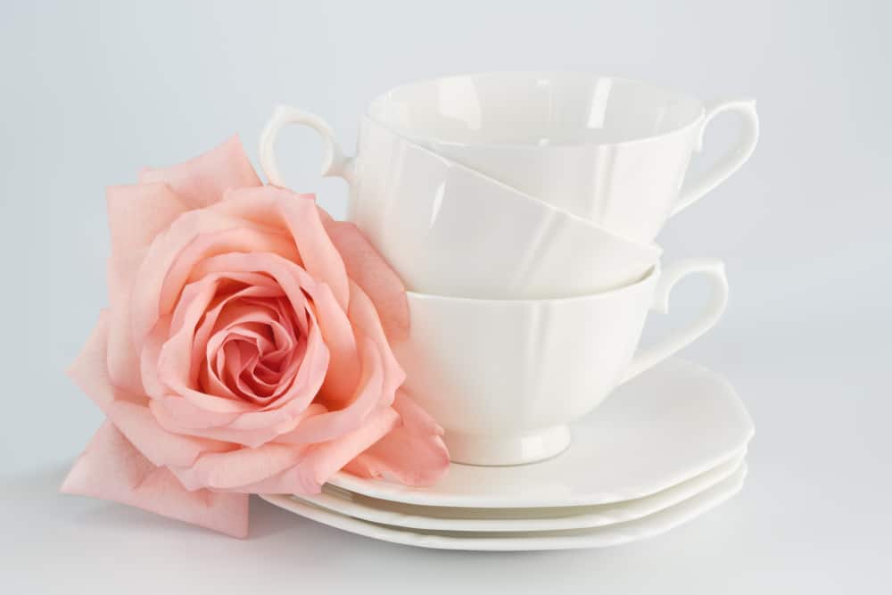 Fine china cups sit with a rose garnish.