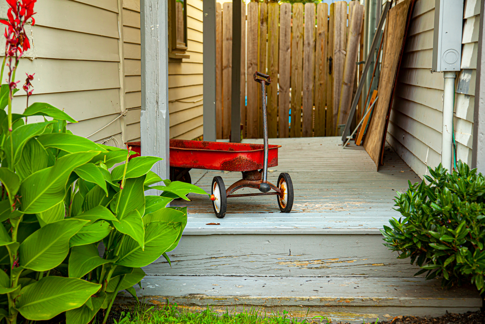 A red toy wagon sits on some porch steps.