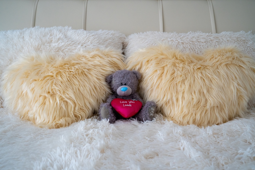 A plush comforter with a teddy bear on it awaits you!