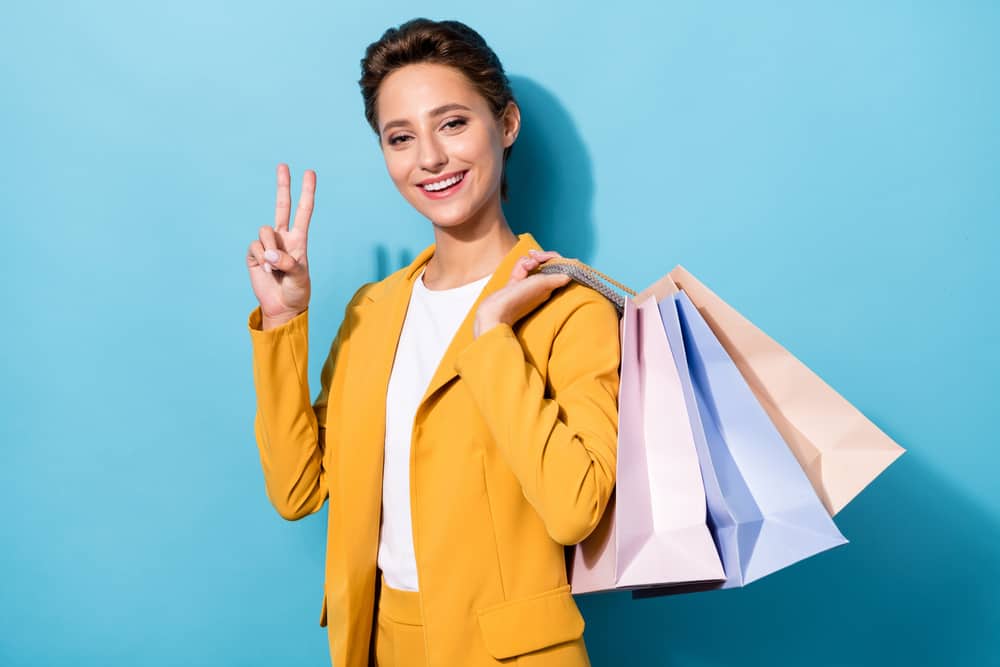 A happy shopper smiles and holds up her shopping bags.