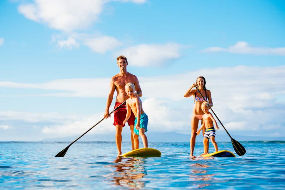 A family of four paddleboards together on a sunny day.