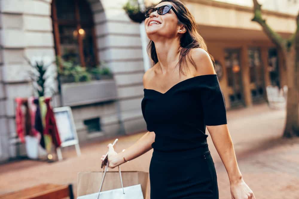 A woman smiles as she enjoys shopping at high-end stores.