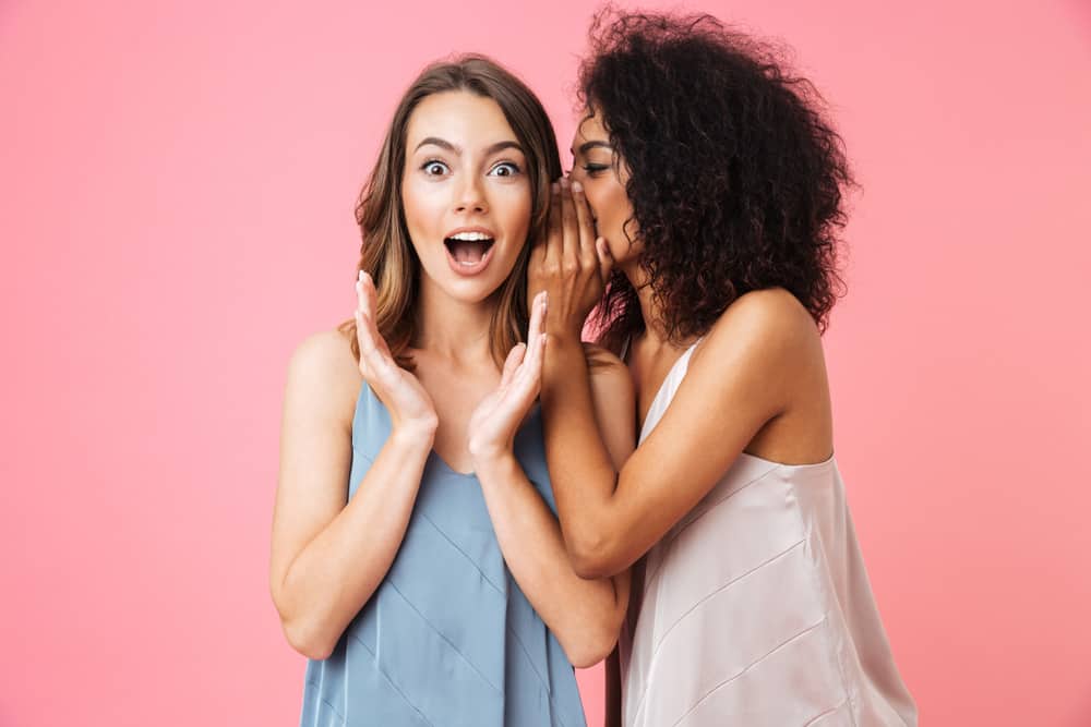 A woman shares a secret with her friend.