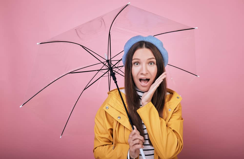 A woman holds an umbrella and wears a rainjacket to stay dry.