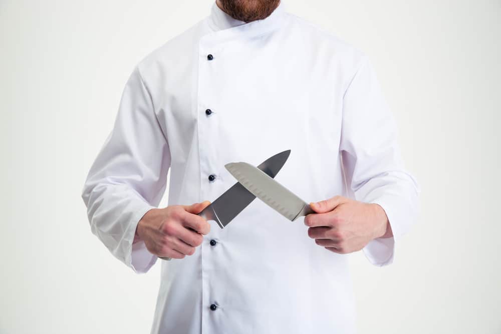 A chef proudly displays a pair of knives.